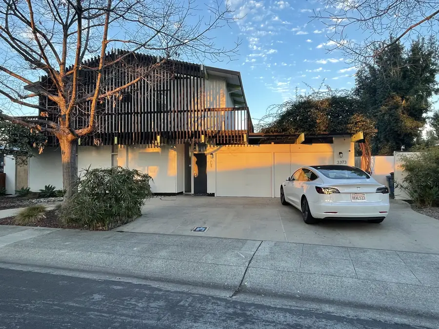 An Eichler with a bright orange courtyard wall and a vertical timber privacy screen.
